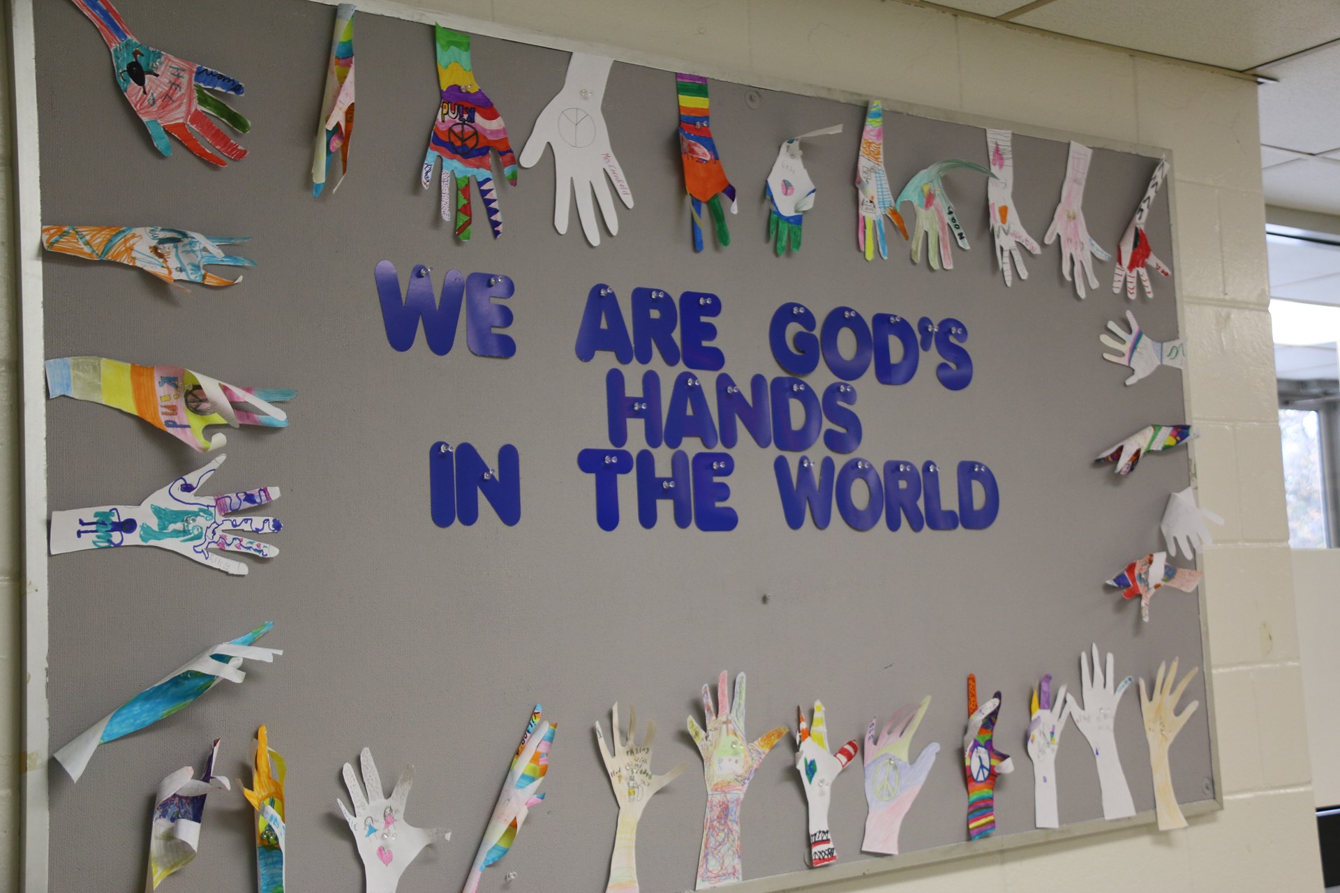 Bulletin Board with student artwork showing "We are God's Hands in the World"