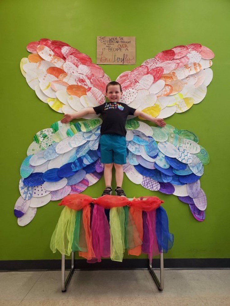 Student posing as body of butterfly with wings.