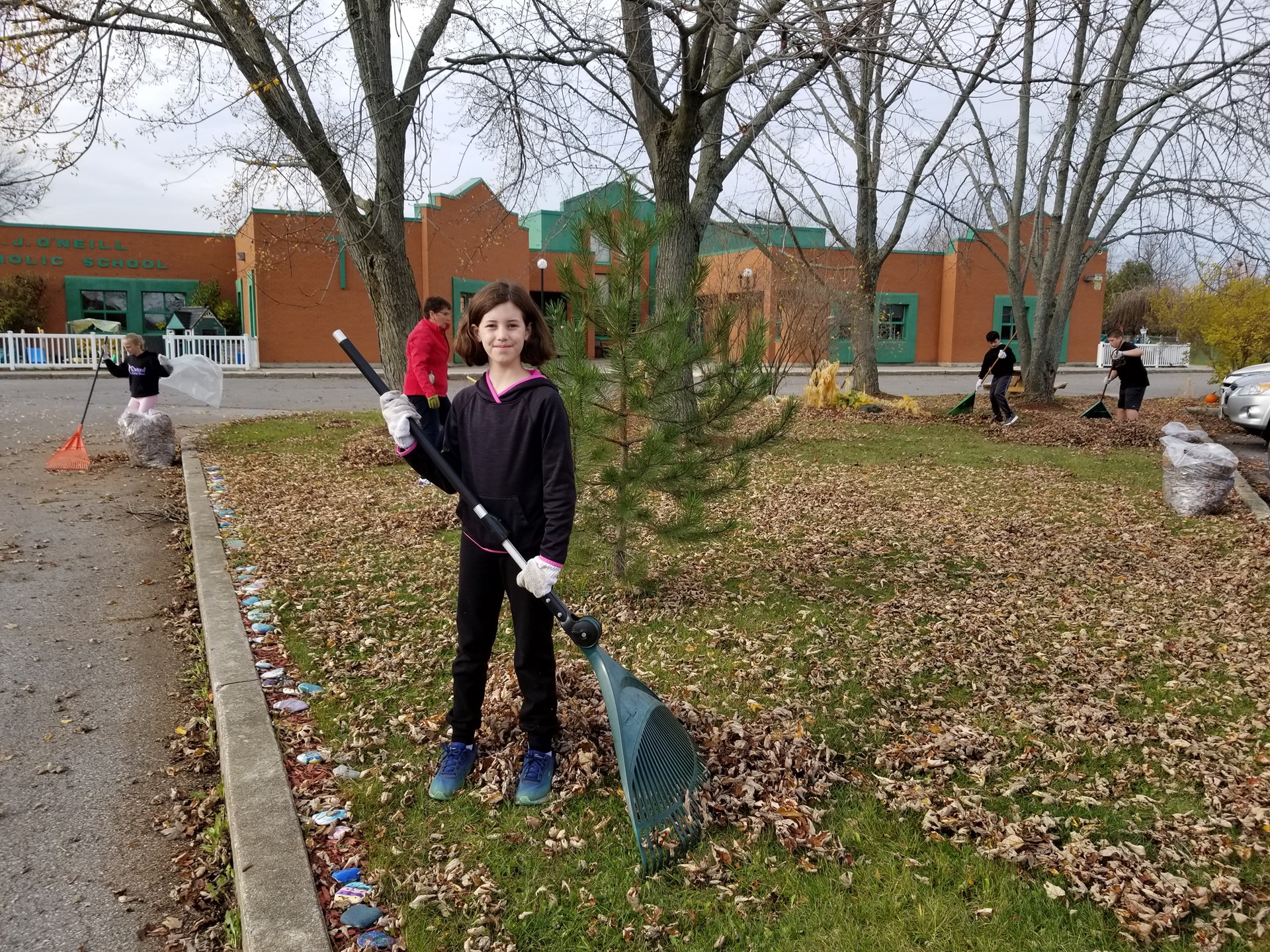 Students raking and cleaning up school yard.