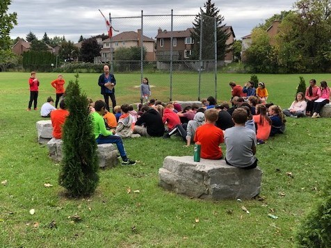 Students outside learning about the significance of Orange Shirt Day