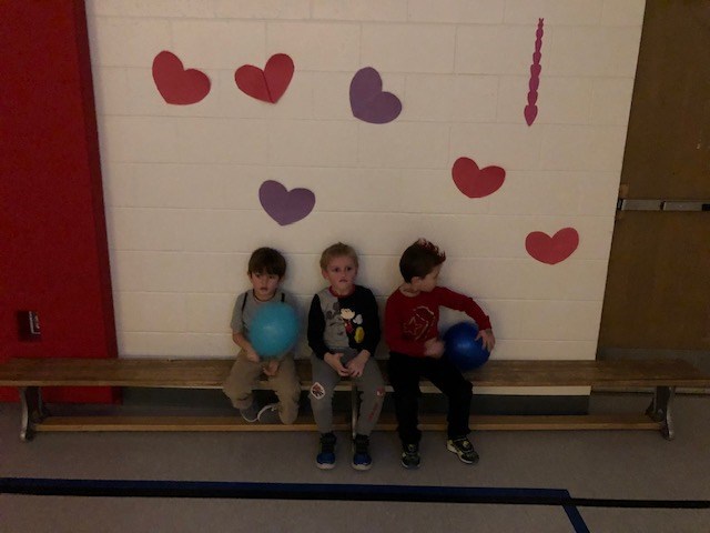 Boys sitting in front of Valentines Day poster.