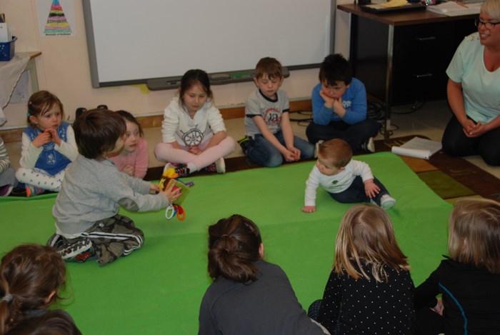 Baby on floor with students learning about Roots of Empathy at Holy Name